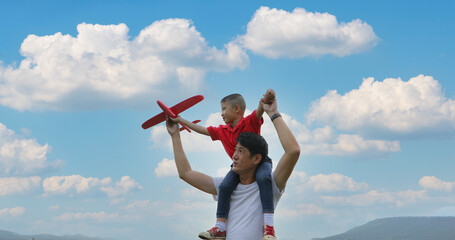 Father and son playing toy airplane on the Meadow at sunset with happy emotion. Family, Holiday and Travel concept.