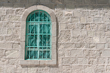 Green window with wrought iron grating and stone wall