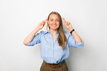 Smiling young business lady crossing fingers and wishing for a good luck