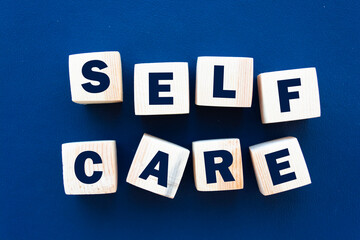 SELF CARE - text on wooden cubes on a blue background