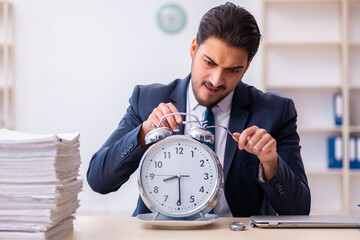 Young businessman employee eating alarm-clock
