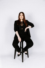 Fototapeta premium The girl is sitting on a chair in a sexy costume. Nice model. fashion. White background. noise effect