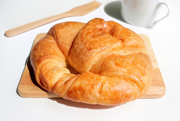 Delicious, fresh croissant on the wooden cutting board and nature sunlight from window.