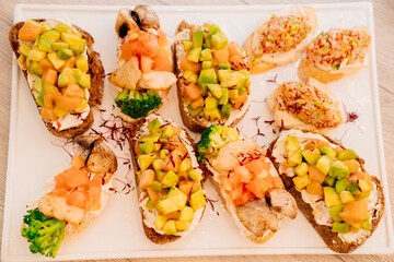 assorted bruschetta with salmon, avocado, broccoli, meat, salad and cheese.