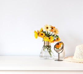 Colorful calendula flowers in a vase on the white table composition. Copy space - obrazy, fototapety, plakaty