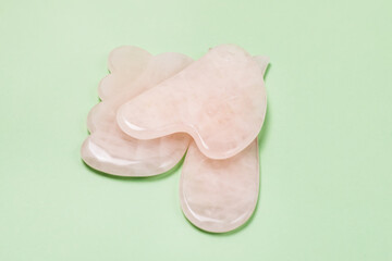 Close Up Cosmetic Massage Pink Jade Gua Sha Scrapers for Facial and Body Skin Care Spa and Beauty Concept Green Background