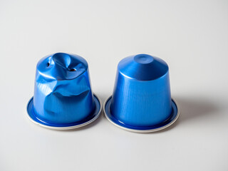 two blue aluminum capsules with ground coffee on a white background. One of them is used. Storage and processing of materials. Eco-friendly products
