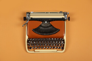 Vintage typewriter on brown background, top view