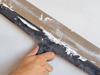 the hand of a worker with a long spatula that works on the wall. Interior work, construction concept