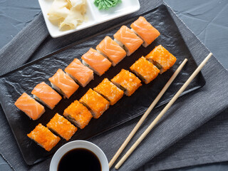 roll Philadelphia and California on a black plate. Top view, flat lay. ginger, wasabi and soy sauce nearby. traditional Japanese cuisine
