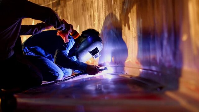 Welding  arc argon worker male repaired metal is welding sparks industrial construction tank stainless oil inside confined spaces.