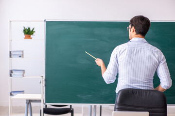 Young male teacher in front of blackboard