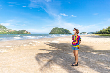Asian women wearing colorful clothes Wear a mask to prevent coronavirus infection Travel to the sea, beach, look at the beautiful nature of the sea. the bright blue sky during the covid epidemic.