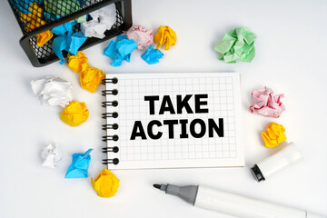 On the table is a basket, multi-colored paper and a notebook with the inscription - Take Action