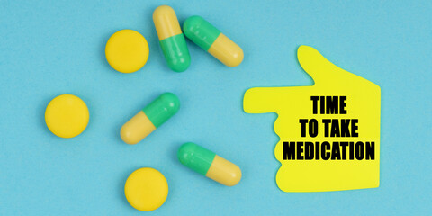 On a blue background, there are pills and a hand-sticker with the inscription - time to take medication