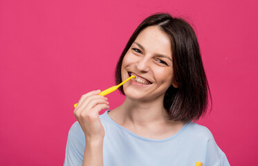 Beautiful happy young woman with single tufted toothbrush on blank pink background