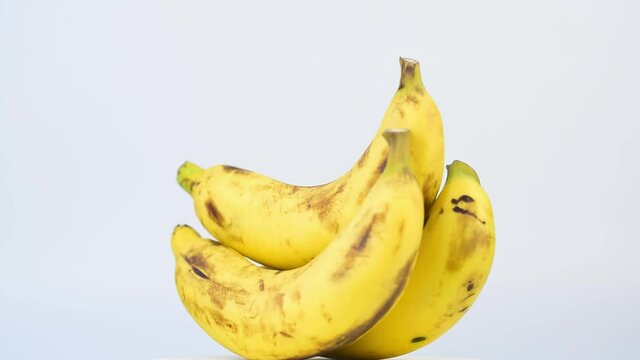 Closeup group of ripe yellow bananas rotating 360 degrees on white background.