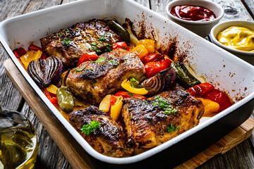 Tasty roasted ribs with baked potatoes and vegetables served on frying pan on wooden table
