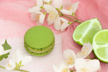 Fototapeta na wymiar green macaroon cake on a pink background with a slice of lime. Lime macaroon with green cream. Round mint dessert. High quality photo