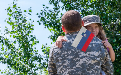 Reunion of soldier from Slovenia with family, daughter hug father. A girl holds the flag of...