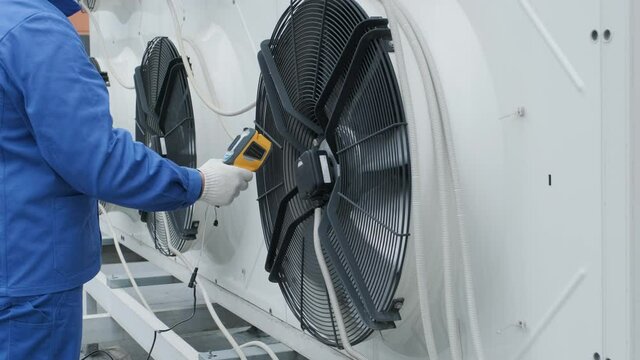 Technician uses a thermal imaging infrared thermometer to check the condensing unit heat exchanger