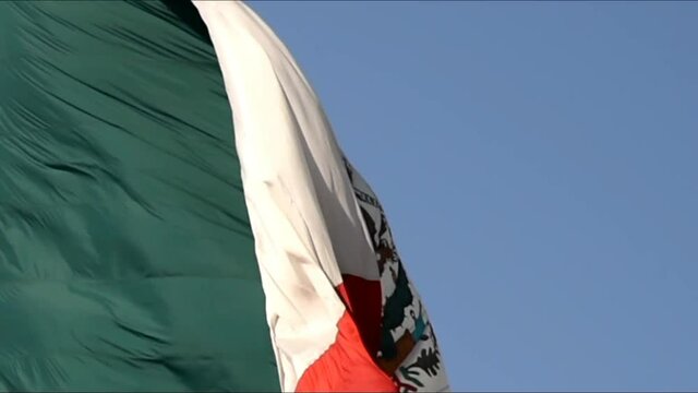 Mexican flag agitated in the wind,closeup,Mexican coat of arms in the foreground