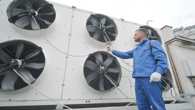 Technician uses a thermal imaging infrared thermometer to check the condensing unit heat exchanger