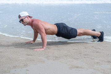 Young man stretching and exercising on the beach, on the sandy beach, relaxing on vacation 