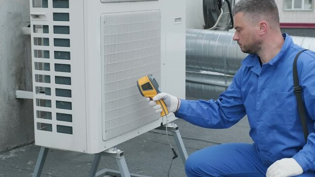 Technician uses a thermal imaging infrared thermometer to check the condensing unit heat exchanger