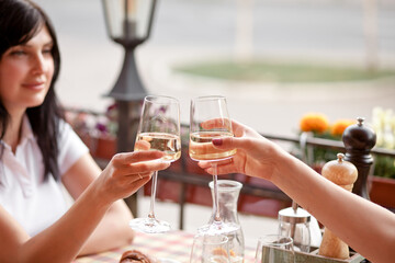 Obraz na płótnie Canvas Women holding the glasses of white wine making a toast. Woman cheers.