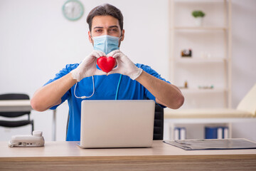 Young male doctor cardiologist working in the clinic during pand