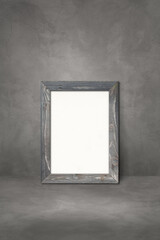 Wooden picture frame leaning on a dark concrete wall