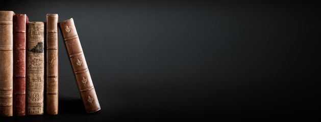 Row of old books on black background banner