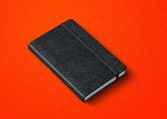 black closed notebook isolated on red