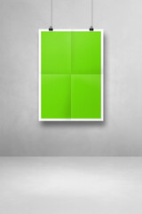 green folded poster hanging on a clean wall with clips