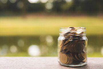money saving, business financial growth, economy budget and investment concept. golden coins in jar and coin stack growth up on green blur nature background.