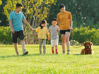 Happy family of four walking dogs in the park