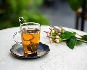 cup of fresh aromatic tea on table with nature flowers background