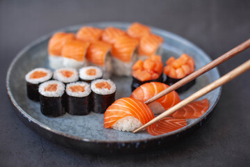 Traditional japanese nigiri sushi with salmon placed between chopsticks