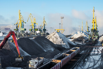 Heaps of coal on the territory of the seaport. Coal is unloaded from wagons by all kinds of cranes, then loaded into the holds of sea ships. The work is carried out around the clock