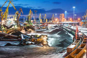 Twilight. Heaps of coal in the seaport. Coal is unloaded from wagons by all kinds of cranes, then loaded into the holds of sea ships.