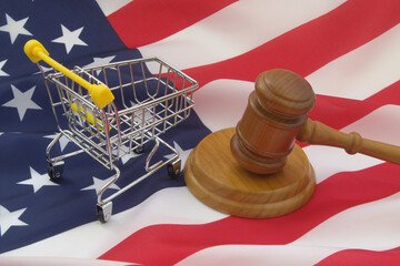 Shopping cart with wooden judge gavel on USA flag. Commercial law and consumers rights in United States concept.	
