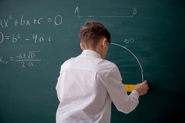 Schoolboy studying geometry in front of blackboard