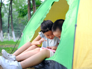 Two kids playing with tablets in the tent