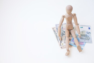 Wooden man sitting on a stack of money. Business concept.