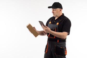 Delivery man with tablet. Courier portrait on white background. Adult courier with box in his hand. Concept guy works with courier tablet computer. Delivery man looks at address in electronic tablet