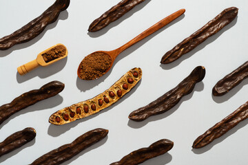Carob bean and powder flat lay on grey background