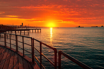 Obraz premium Sunset in Cyprus. View from the Limassol embankment. Sun sets in Mediterranean. Limassol at sunset. Seascape of Cyprus. Evening Limassol. Mediterranean evening landscape. Holidays in Cyprus.