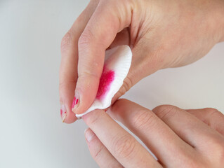 Hands removing red nail polish. Close up.
