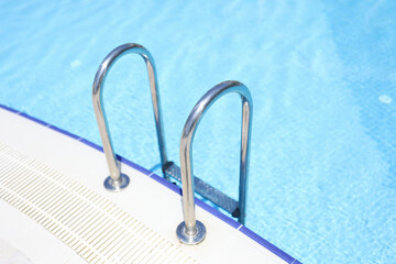 Closeup of stairs to swimming pool with blue water